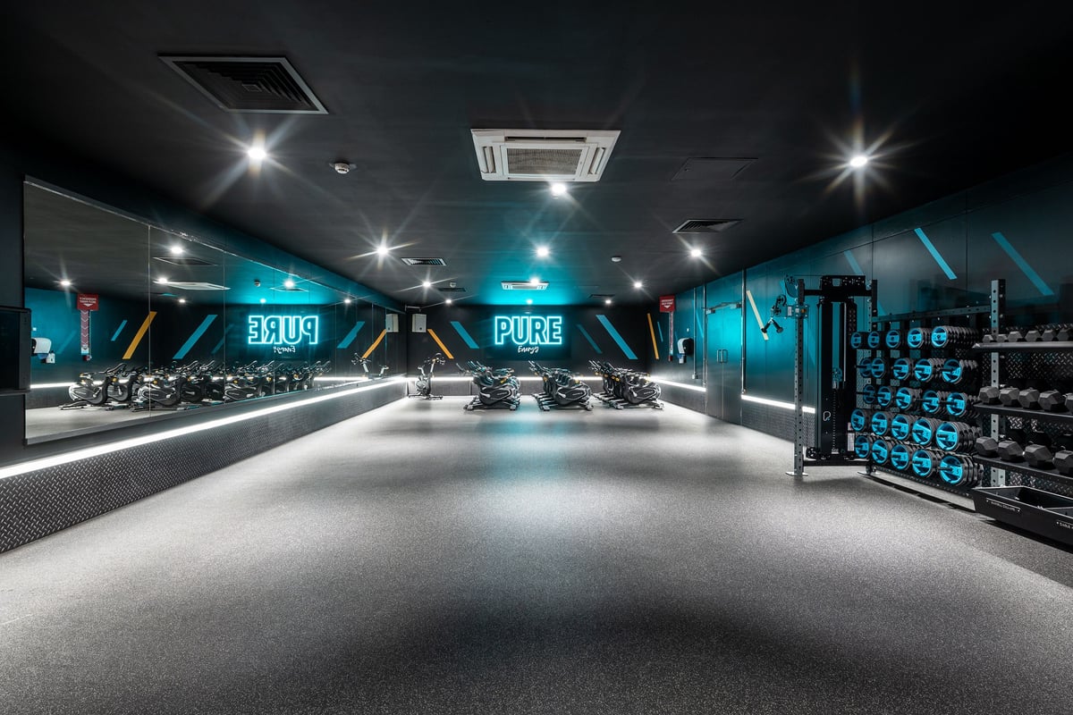 PureGym London Limehouse: Spin bikes, free weights, resistance machines, and rubberized flooring in a dimly-lit studio.