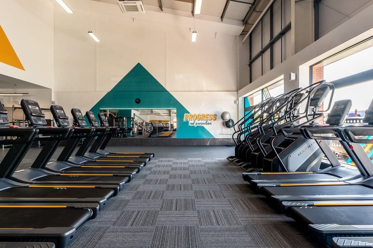 PureGym Crewe Grand Junction Retail Park: Rows of treadmills and exercise bikes in a modern gym space with green accents.
