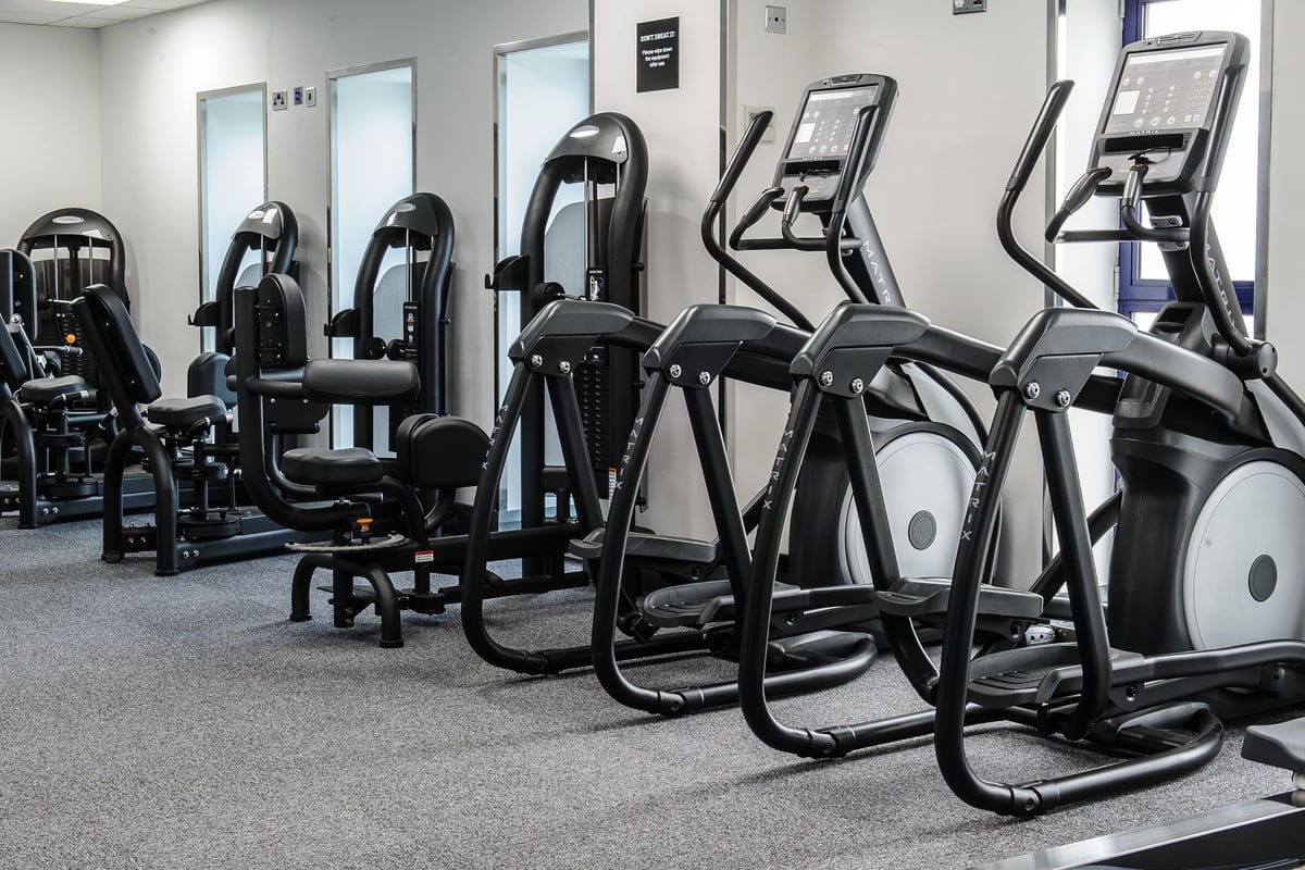 PureGym Denton: Rows of elliptical trainers, resistance machines, and weight stations in a gym setting.