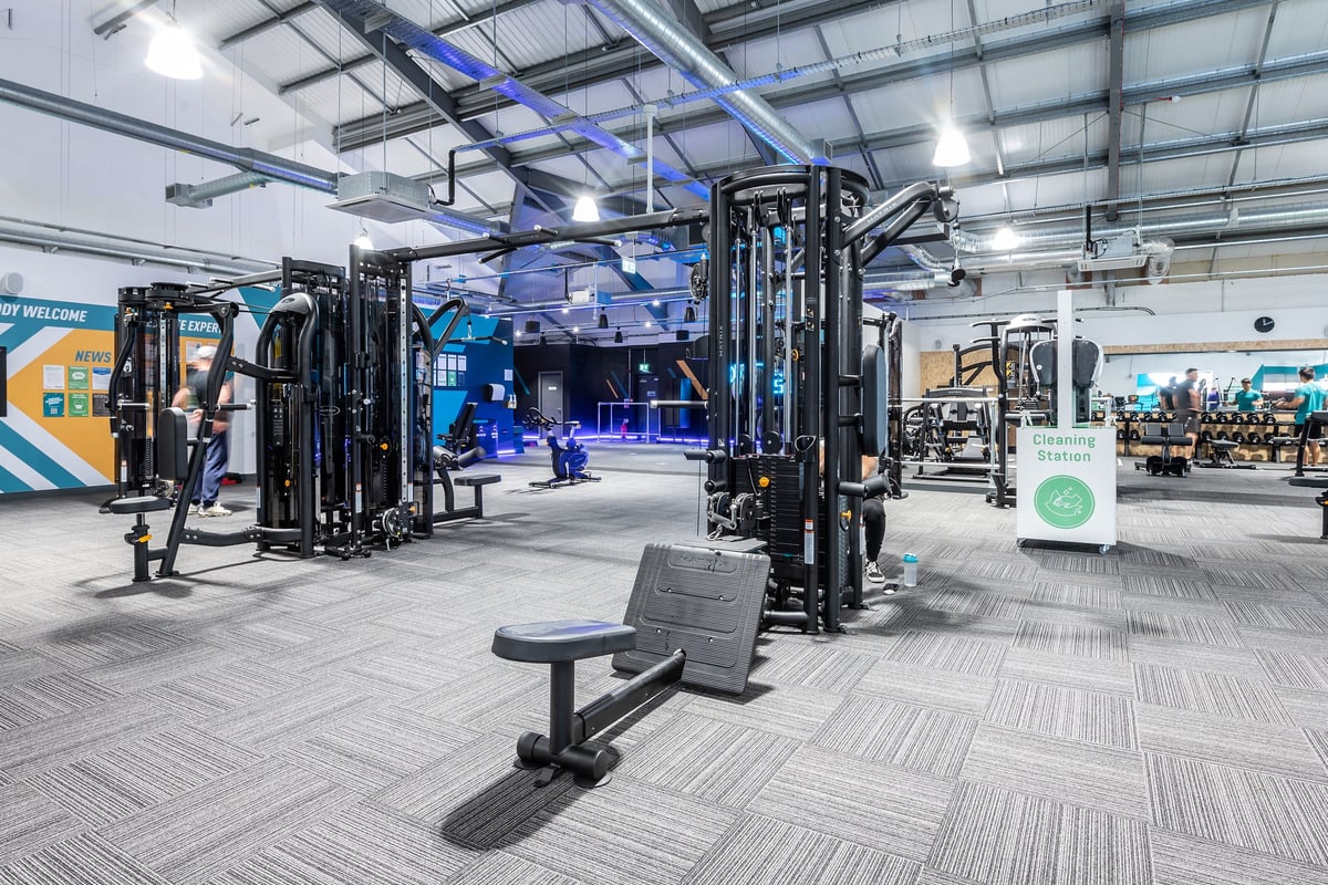 PureGym Stowmarket: Strength training area with squat racks, benches, free weights, and rubberized flooring.
