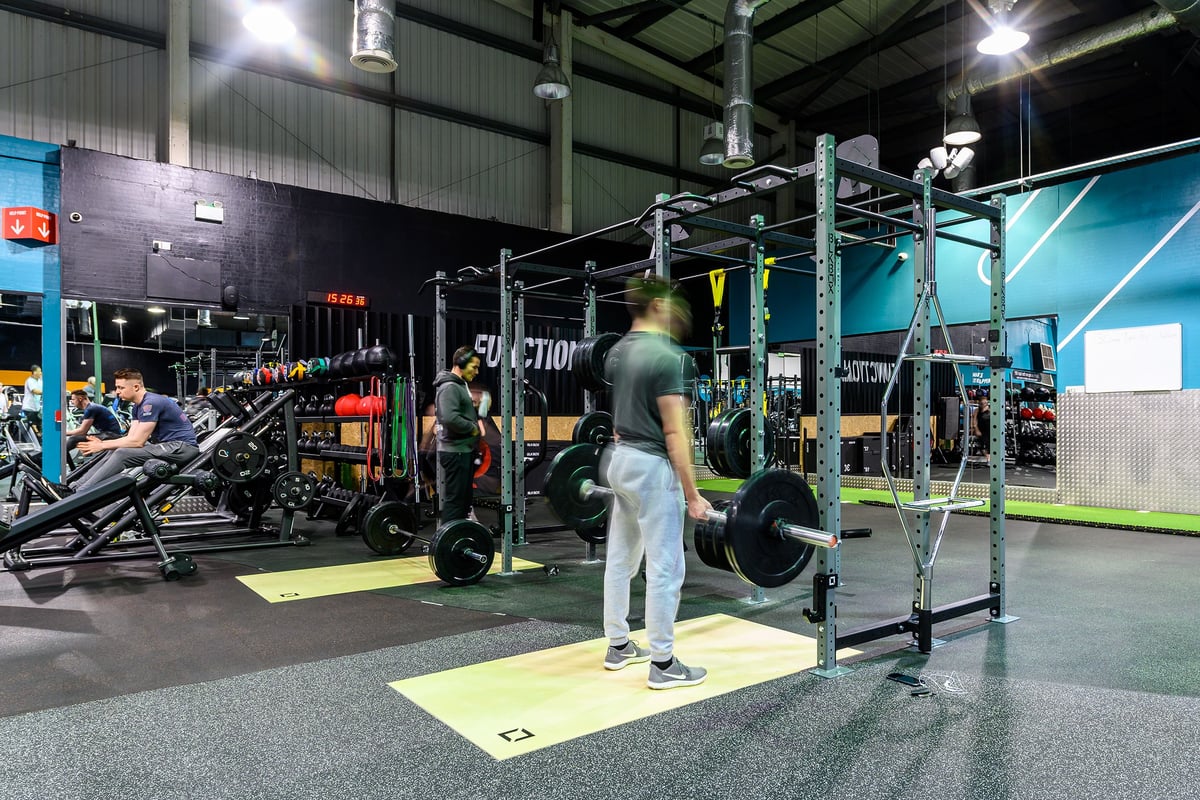 PureGym Bromborough: Weights racks, squat stands, turf area, rubberized floors, and functional training equipment.