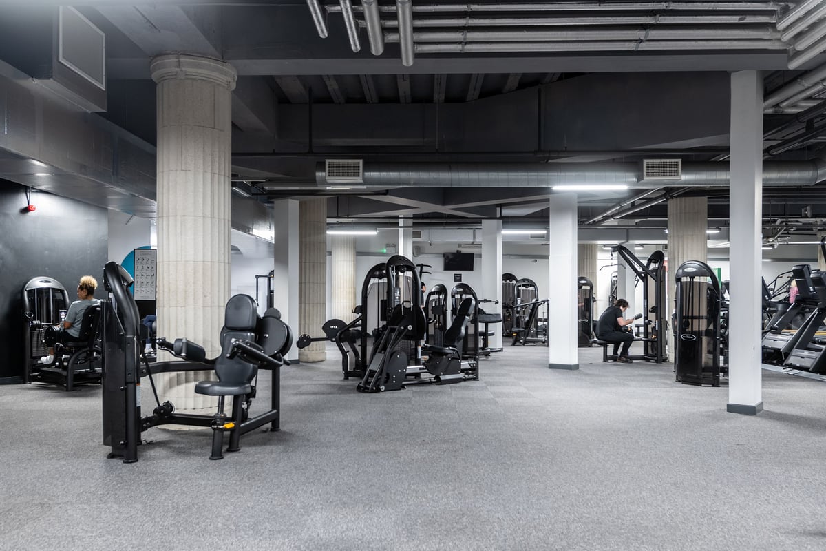 PureGym Liverpool Central: Weight machines, benches, free weights, and mirrored walls inside a dimly lit gym.