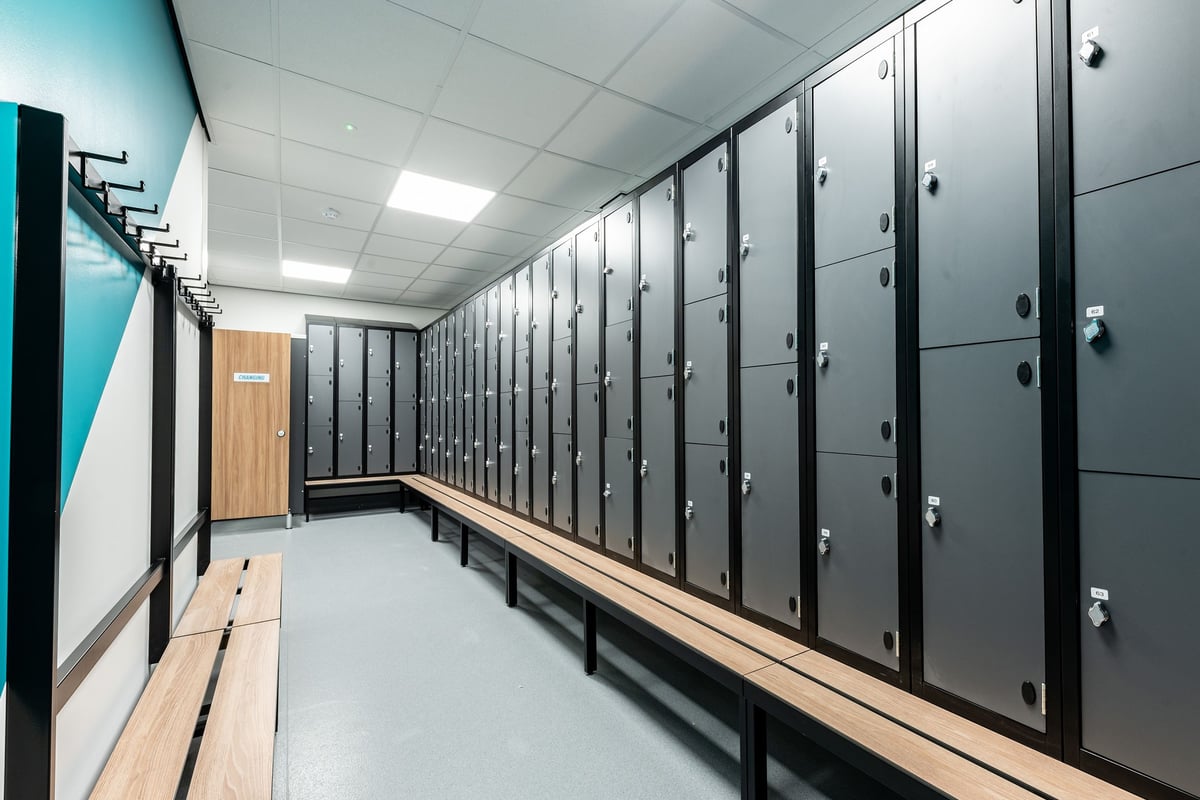 PureGym Caerphilly: Rows of lockers, wooden benches in a changing room setting.