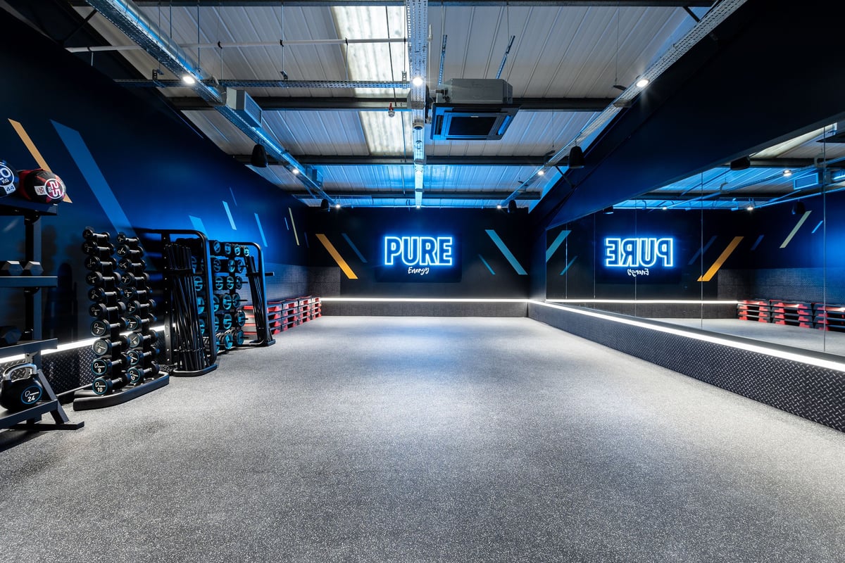 PureGym Letchworth: Weight racks, resistance machines, teal lighting, branded Pure logo wall displays.