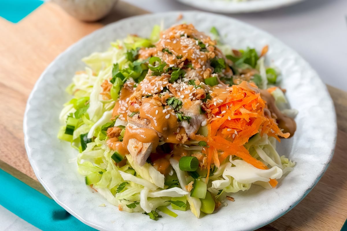 Grilled chicken with sesame seeds and peanut sauce on shredded cabbage and carrot