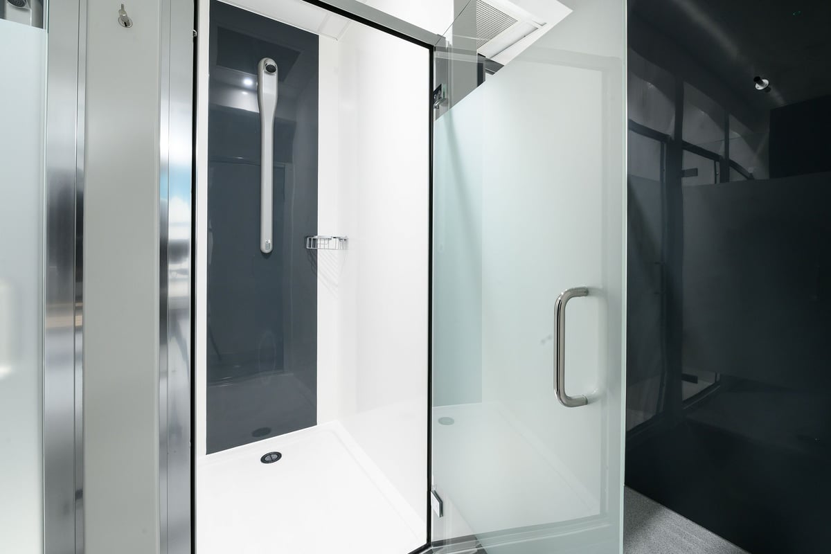PureGym South Ruislip: Shower stalls with glass partitions and metal grab rails.