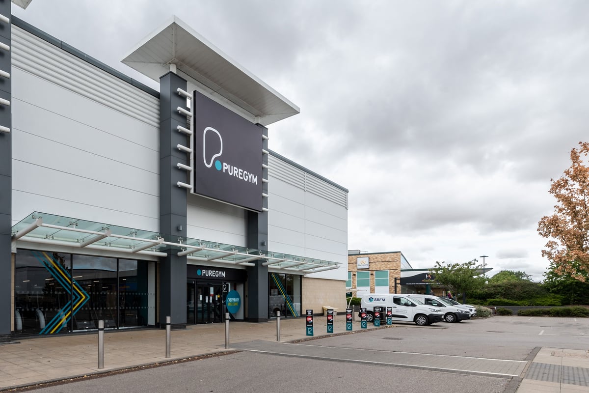 PureGym Peterborough Brotherhood Retail Park: Fitness club exterior with signage, entrance area, and parking spaces.