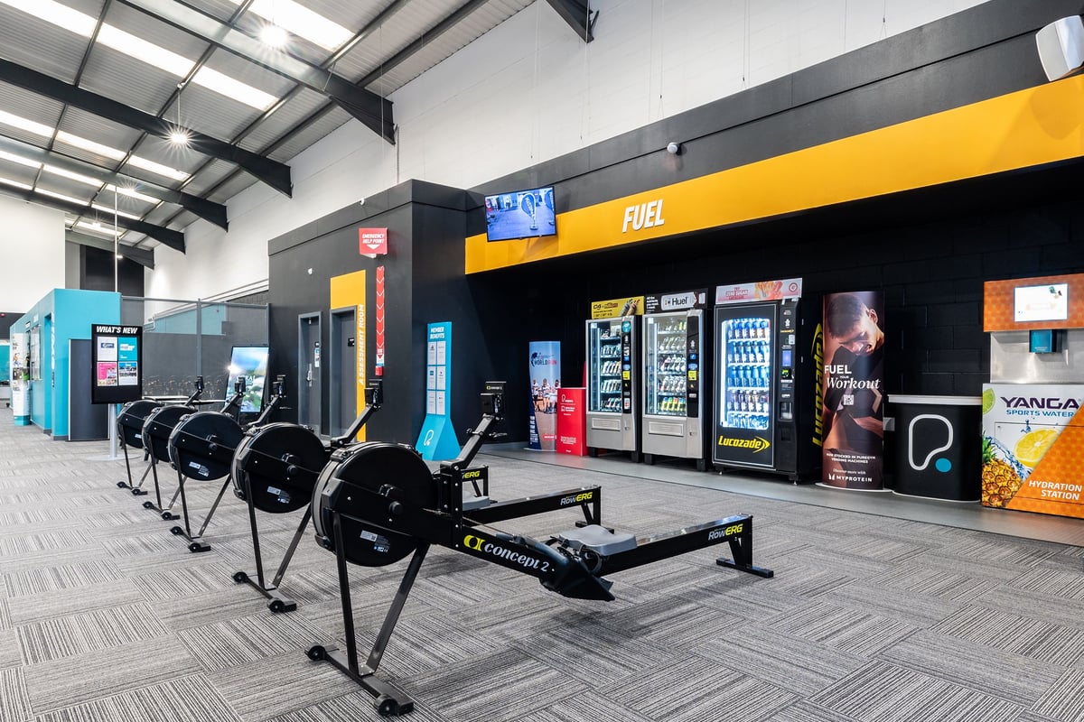 PureGym Leeds Hunslet: Weightlifting area with benches, racks, free weights, and vending machines.