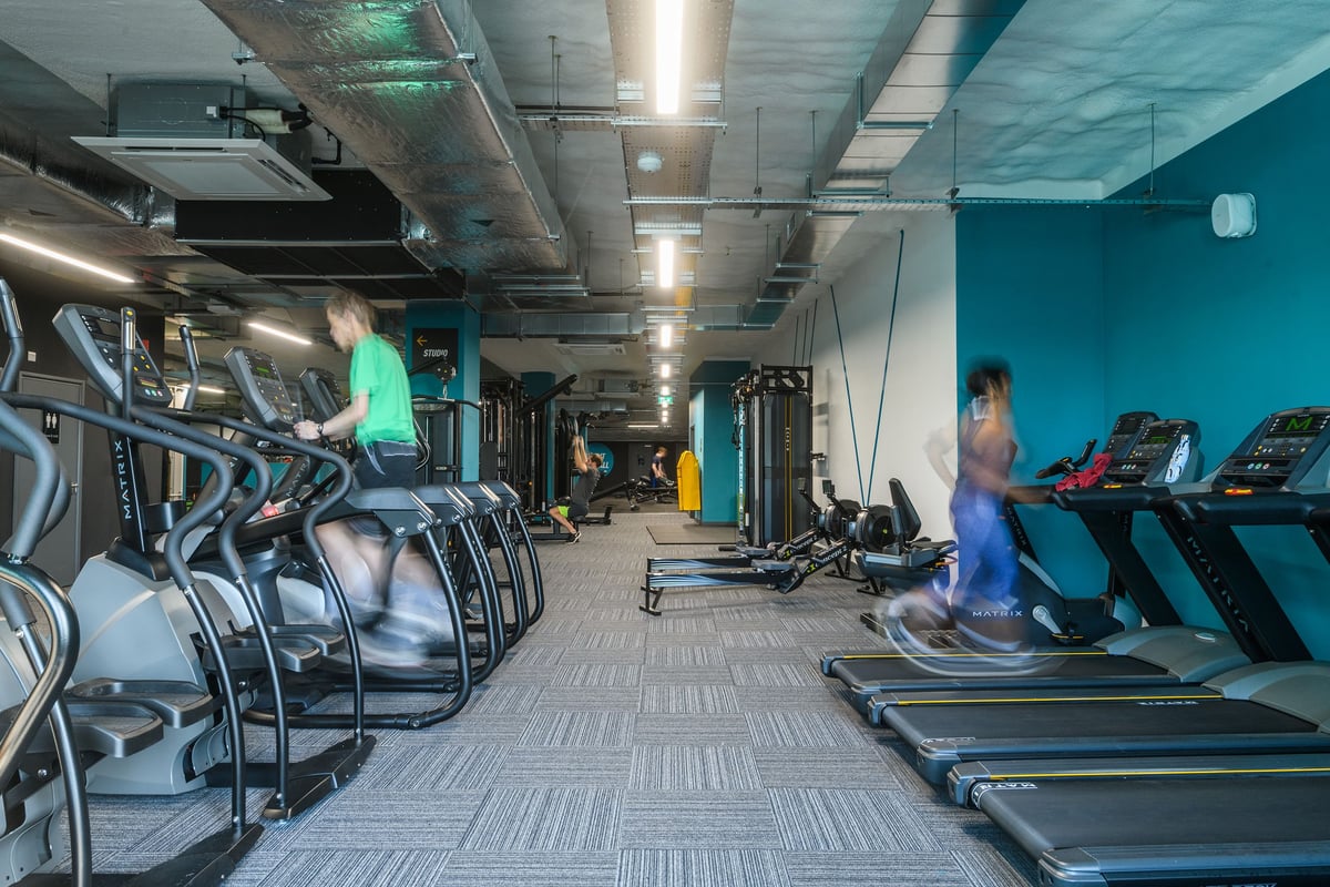 PureGym Hitchin: Rows of treadmills, ellipticals, exercise bikes, and teal walls in a gym facility.