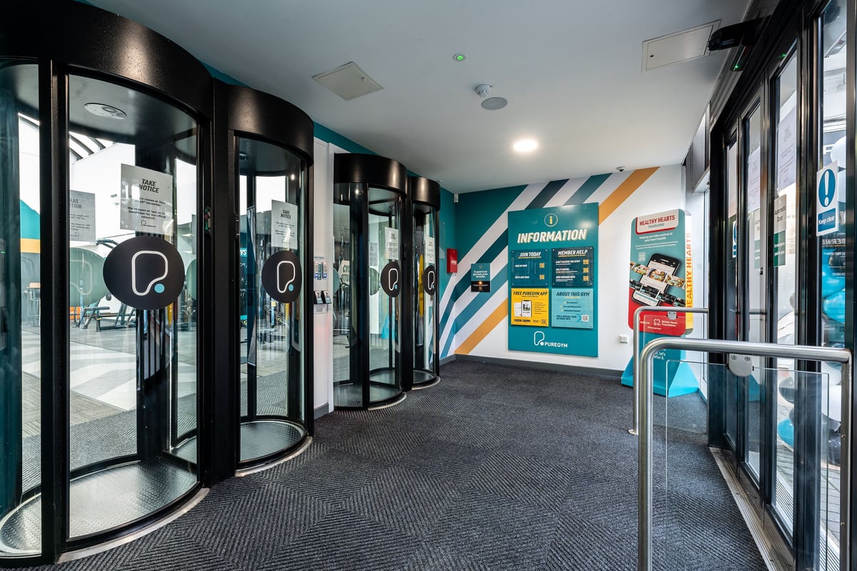 PureGym Purley: Glass entrance vestibule with fitness club branding, turnstiles, and promotional signage.