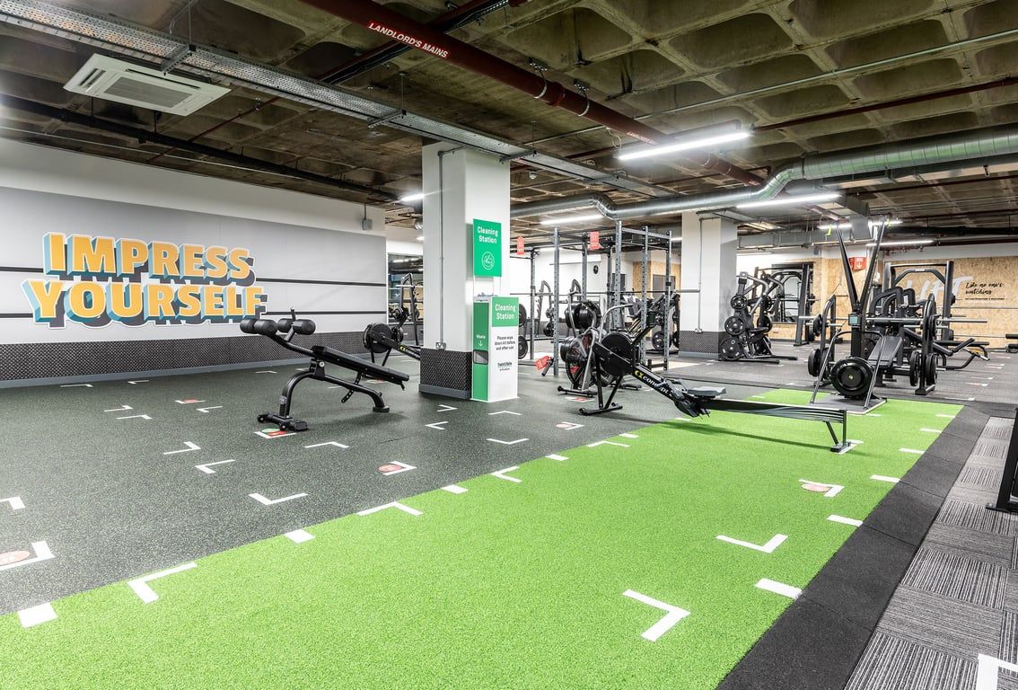 PureGym Maidstone The Mall: Weightlifting area with racks, free weights, green turf, and motivational mural on the wall.