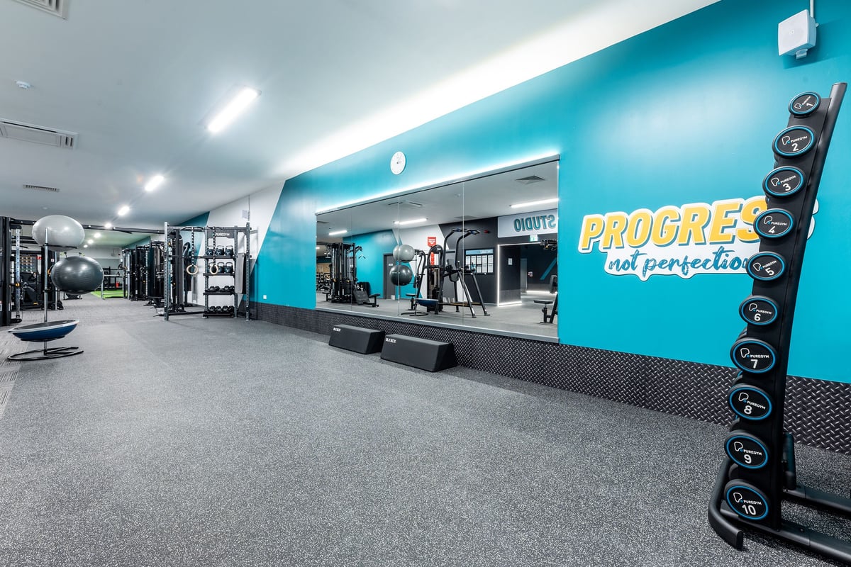 PureGym Selby: Weightlifting racks, resistance machines, treadmills, free weights, and bright teal accent wall.