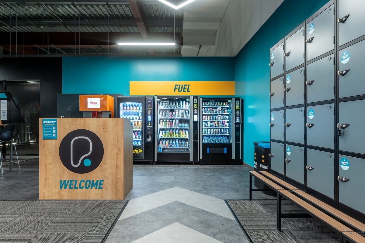 PureGym Craigavon: Vending machines, lockers, and a welcome sign - appears to be a gym lobby or entrance area.