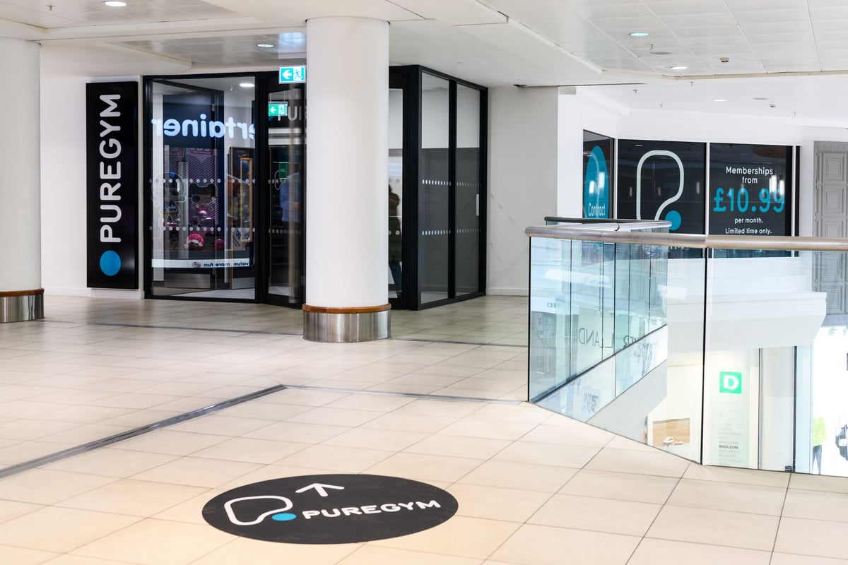 PureGym Basildon: Puregym entrance with turnstiles, digital screens showing membership pricing.