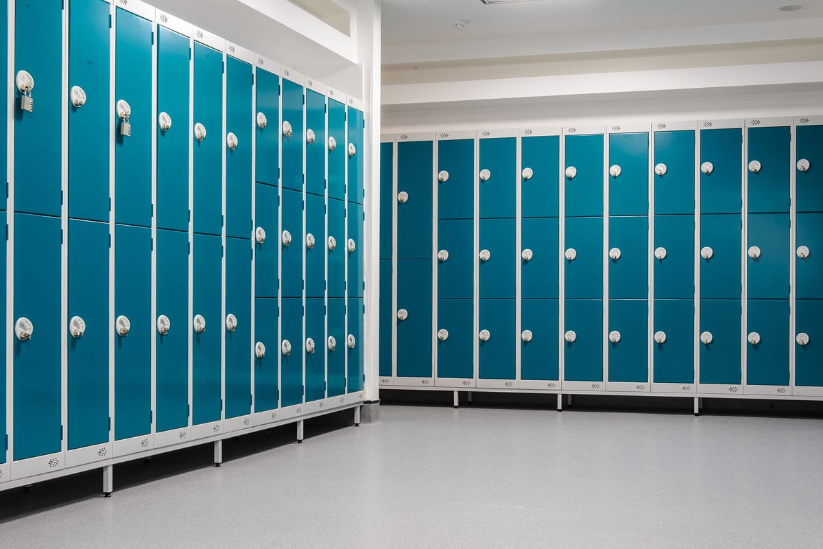 PureGym Denton: Rows of teal lockers with silver handles and benches along the bottom.