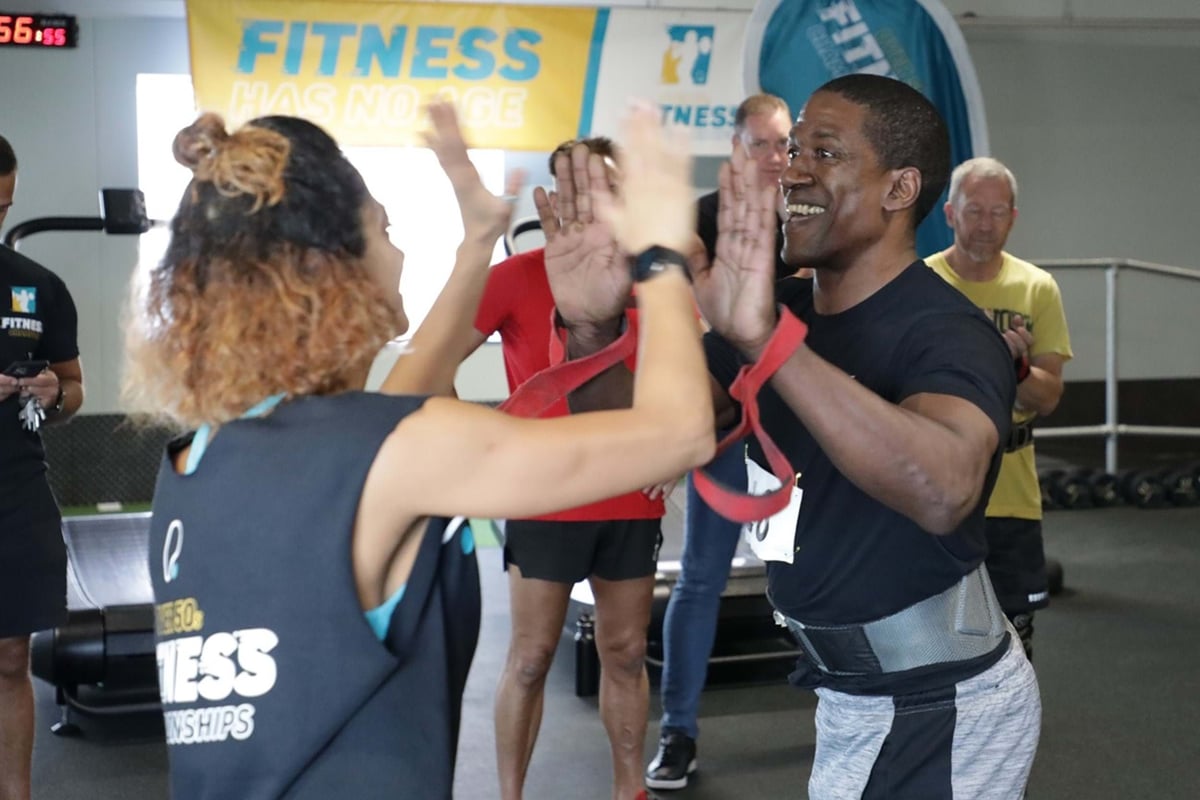 Two people high-fiving during a fitness event with others in the background