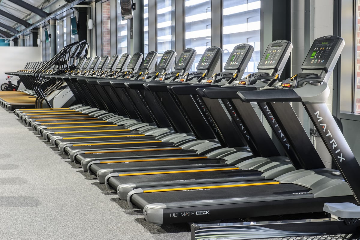 PureGym Leeds Kirkstall Bridge: Rows of treadmills with digital displays lining a bright indoor facility.