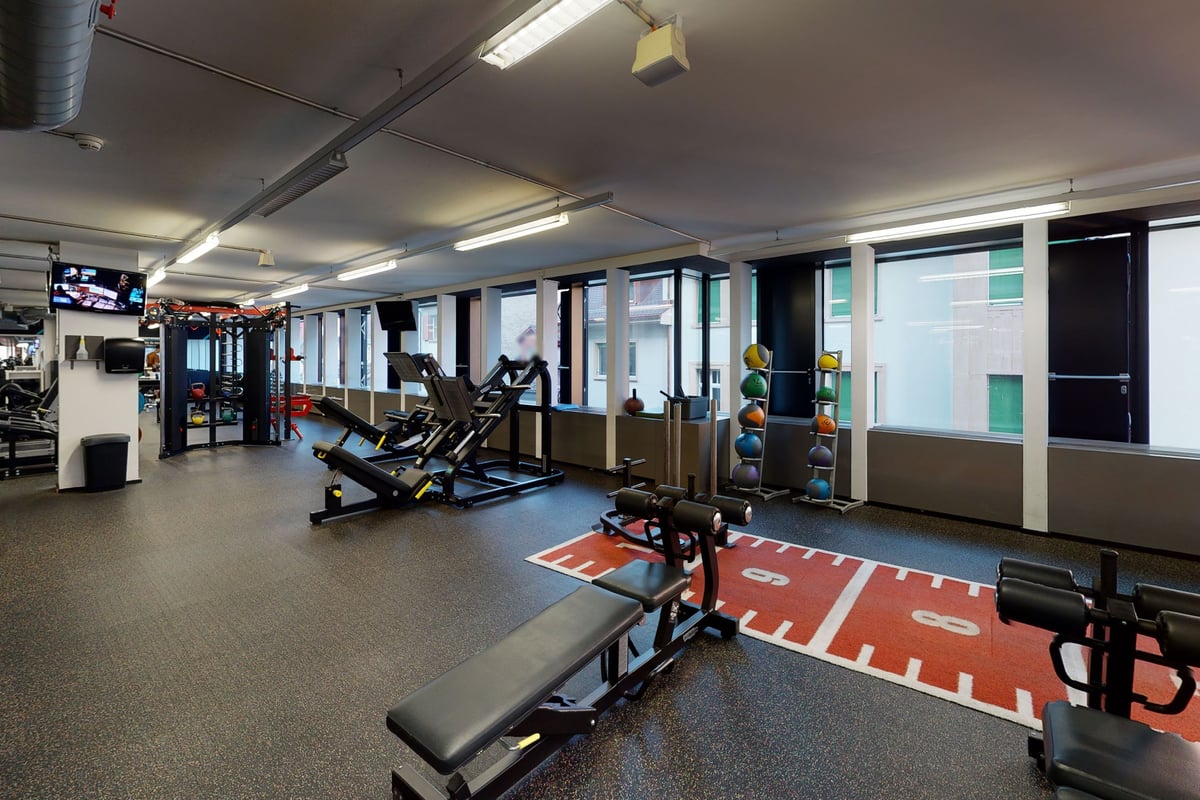PureGym Basel Clara Huus: Fitnessstudio mit Kardiogeräten, Hantelbänken, gummiertem Boden und Bodenmarkierungen.
