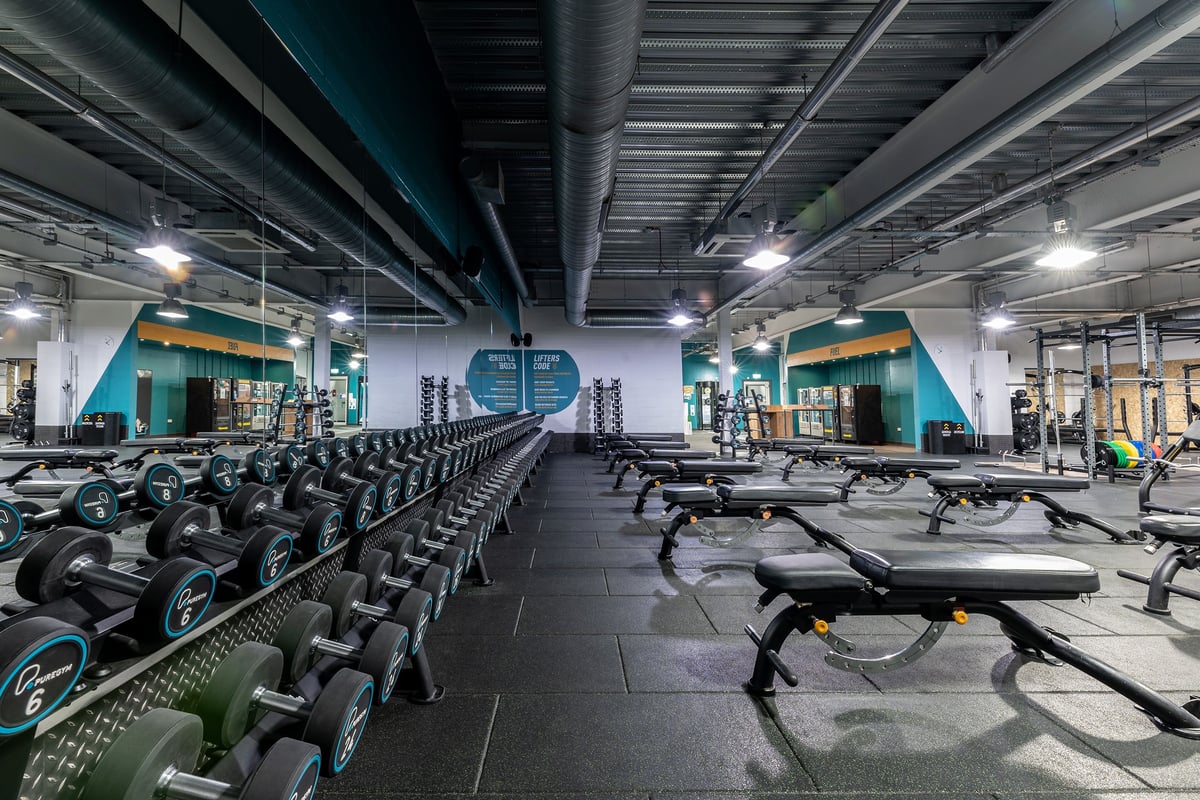 PureGym Nottingham Beeston: Rows of stationary bikes, treadmills, weight benches, dumbbell racks in a dimly lit gym interior.