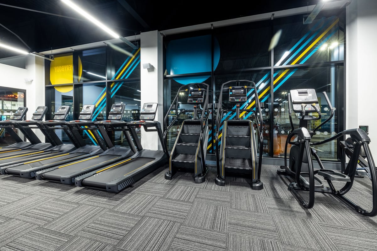 PureGym Washington: Long rows of modern treadmills, bright lighting, and geometric floor pattern in a gym cardio area.