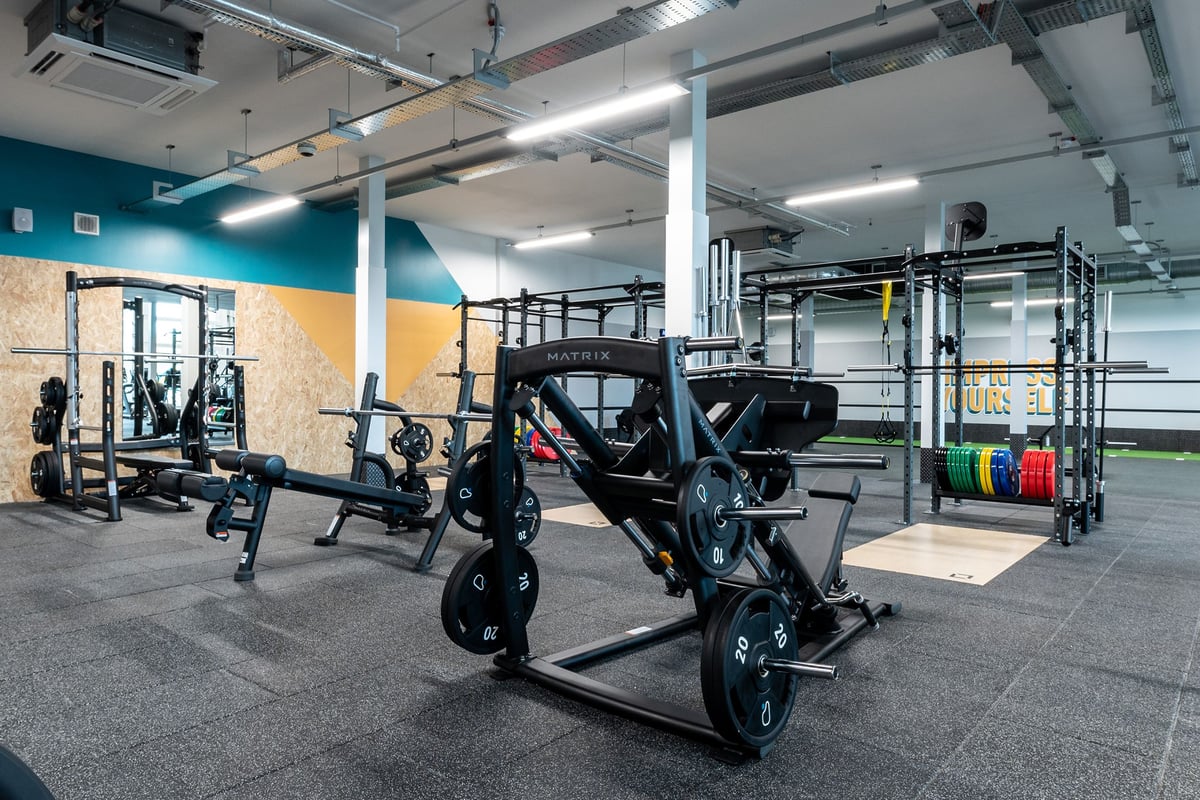PureGym Caerphilly: Strength racks, sled systems, weight plates in rack storage, rubberized gym flooring.