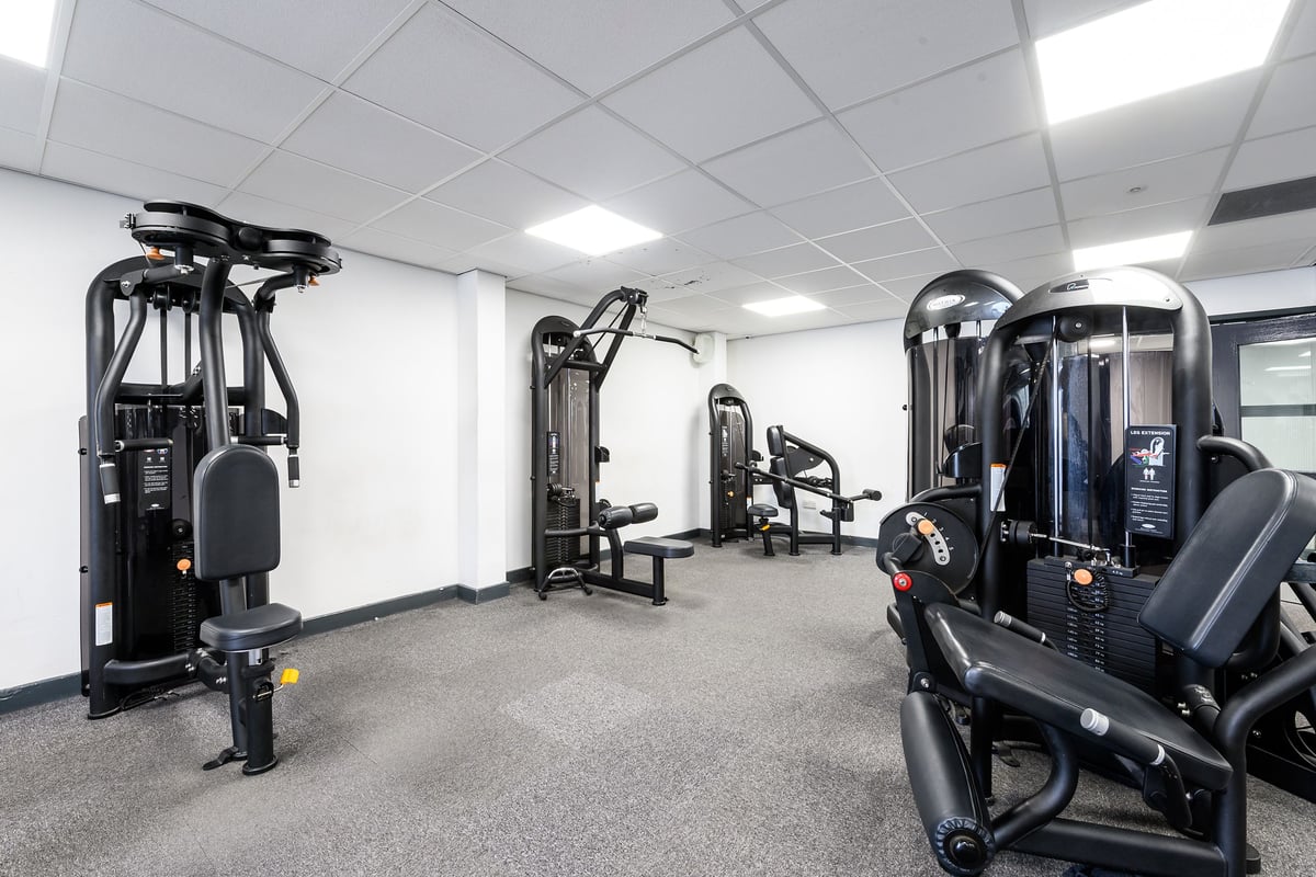 PureGym Burnham: Rows of resistance training machines, adjustable benches, and a mirrored wall in a gym space.