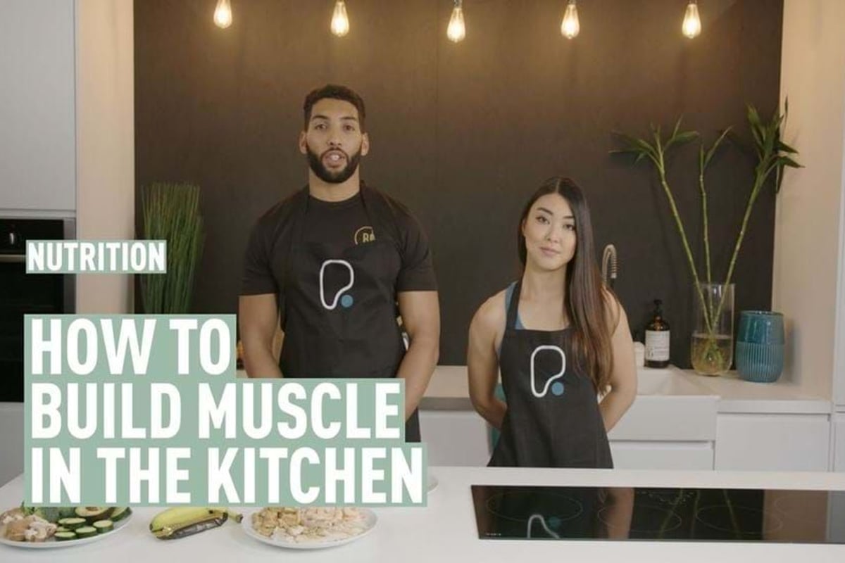 Man and woman wearing aprons standing in kitchen with plates of food on counter
