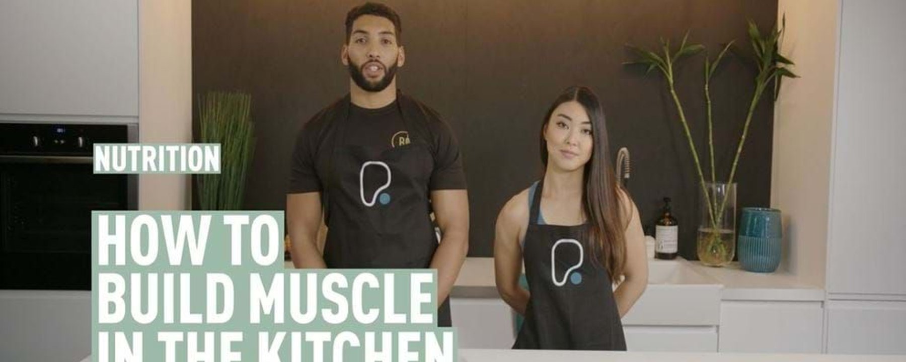 Man and woman wearing aprons standing in kitchen with plates of food on counter