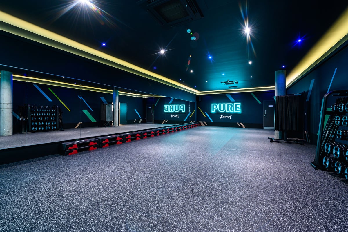PureGym London Fulham: Gym entrance corridor with blue-lit Pure and Tru brandings, red seats.