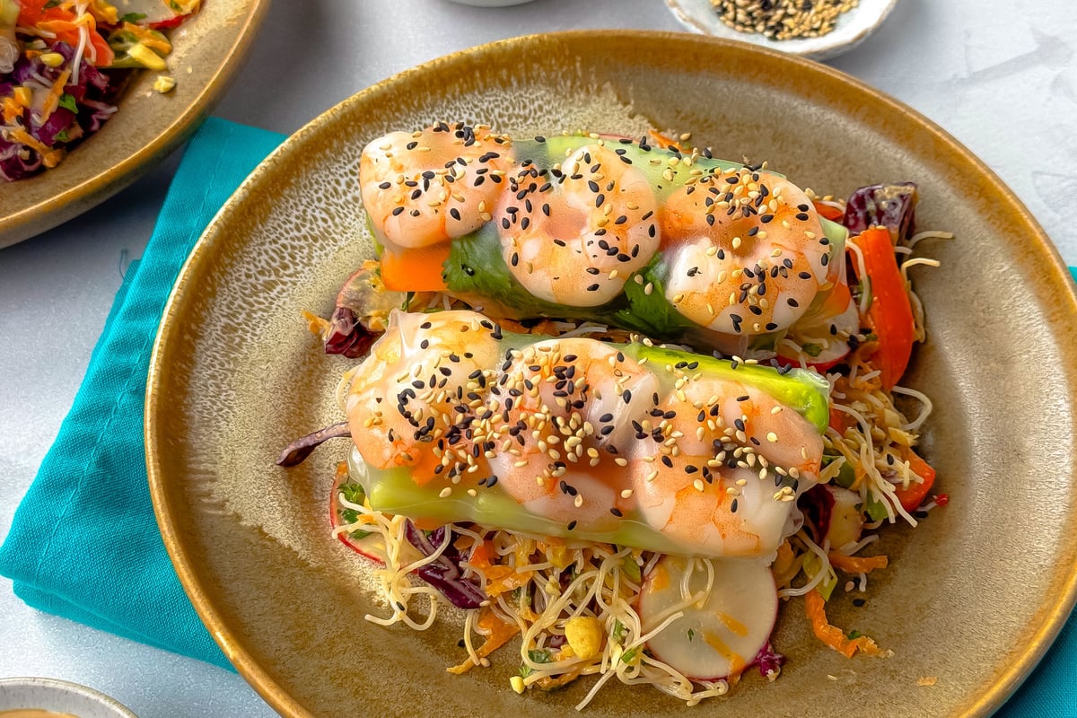 Prawn summer rolls topped with sesame seeds on noodle salad with vegetables