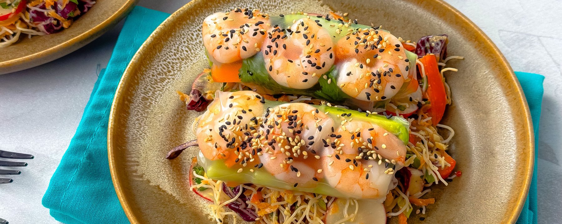 Prawn summer rolls topped with sesame seeds on noodle salad with vegetables