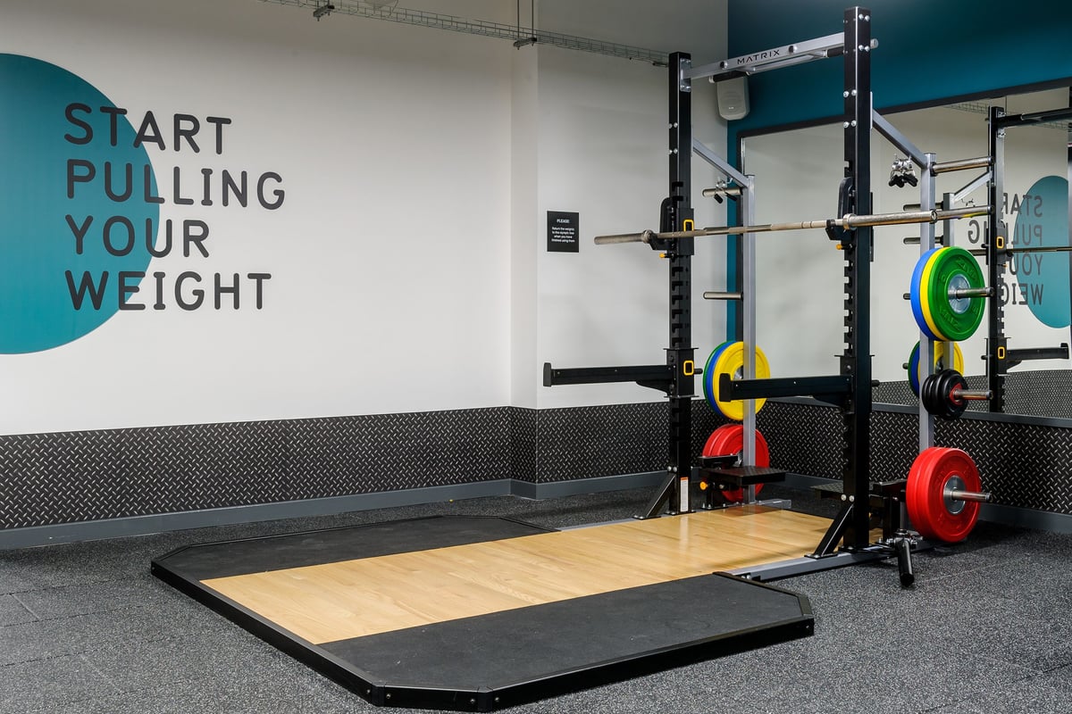 PureGym Glasgow Hope Street: Weightlifting rig, wooden platform, rubber flooring, colourful weight plates.