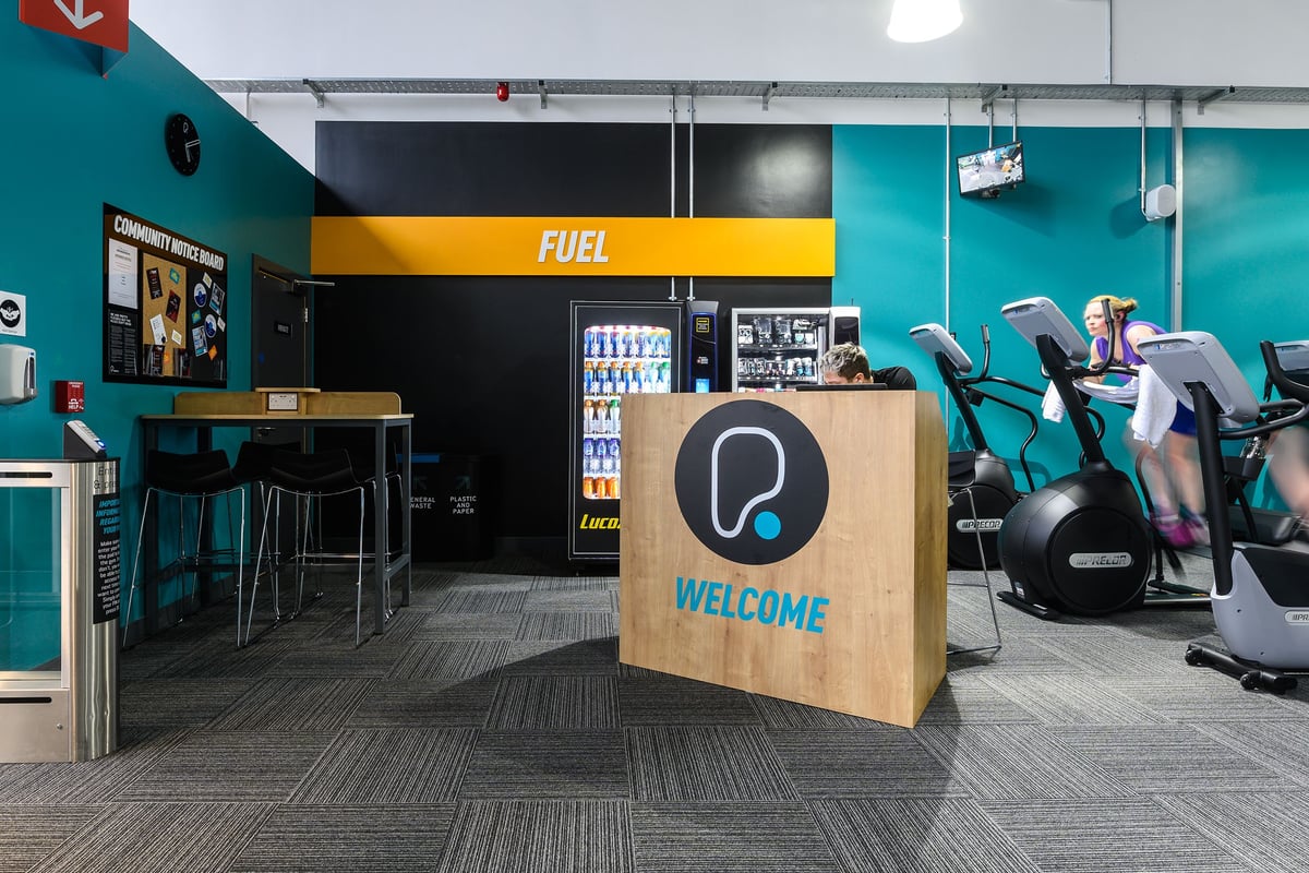 PureGym Bromsgrove Retail Park: Exercise bikes, weight section with treadmills, welcome sign in seating area.