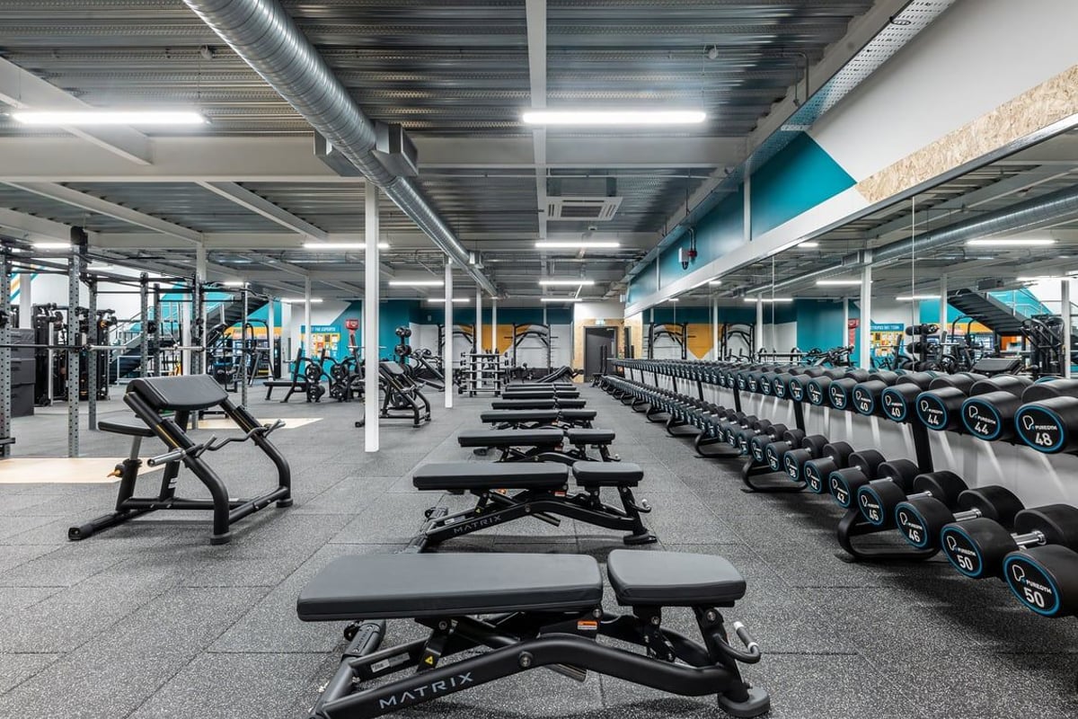 PureGym Eastbourne: Rows of weight benches, dumbbells, and exercise equipment in a spacious gym interior.