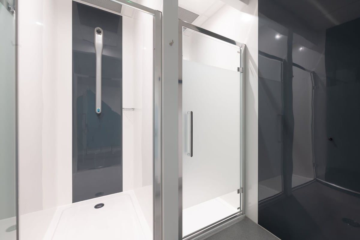 PureGym Plymouth Derriford: Shower cubicles with sliding glass doors, grab rails, and tiled flooring.