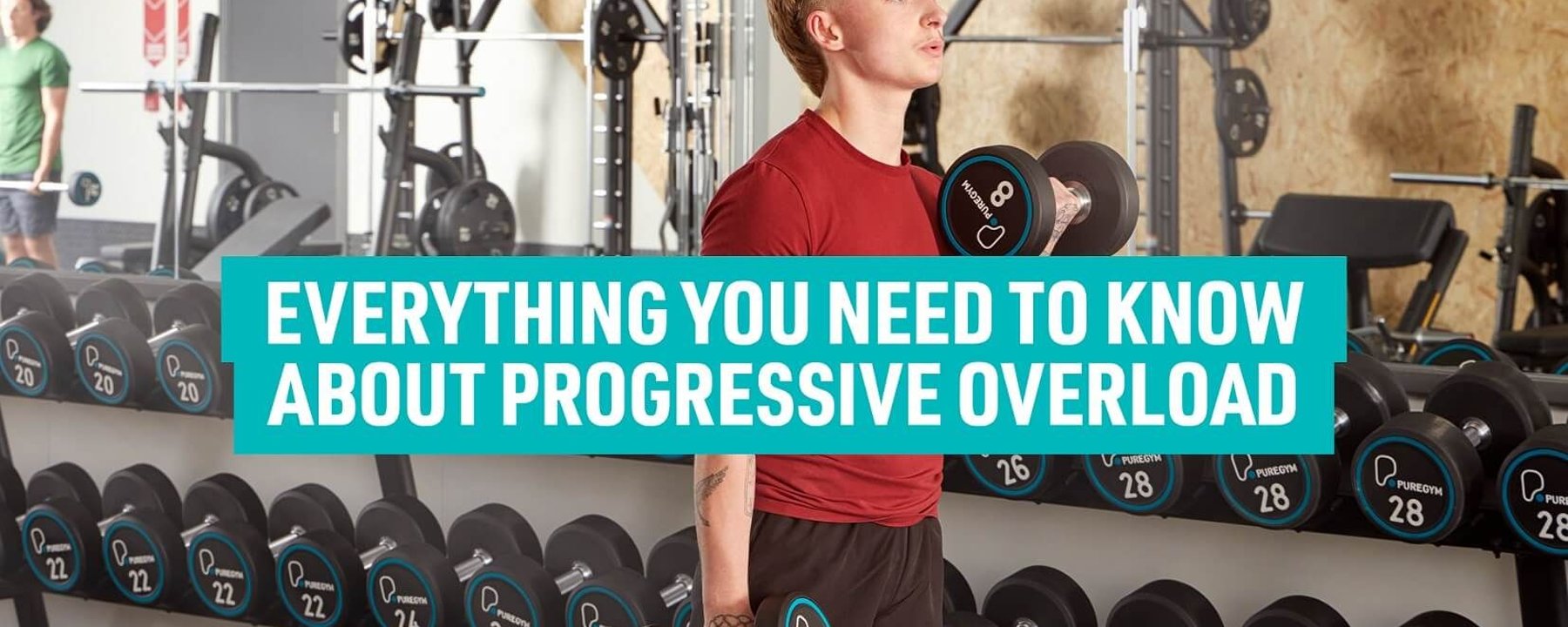 Young man lifting dumbbells in gym with weights on racks behind him