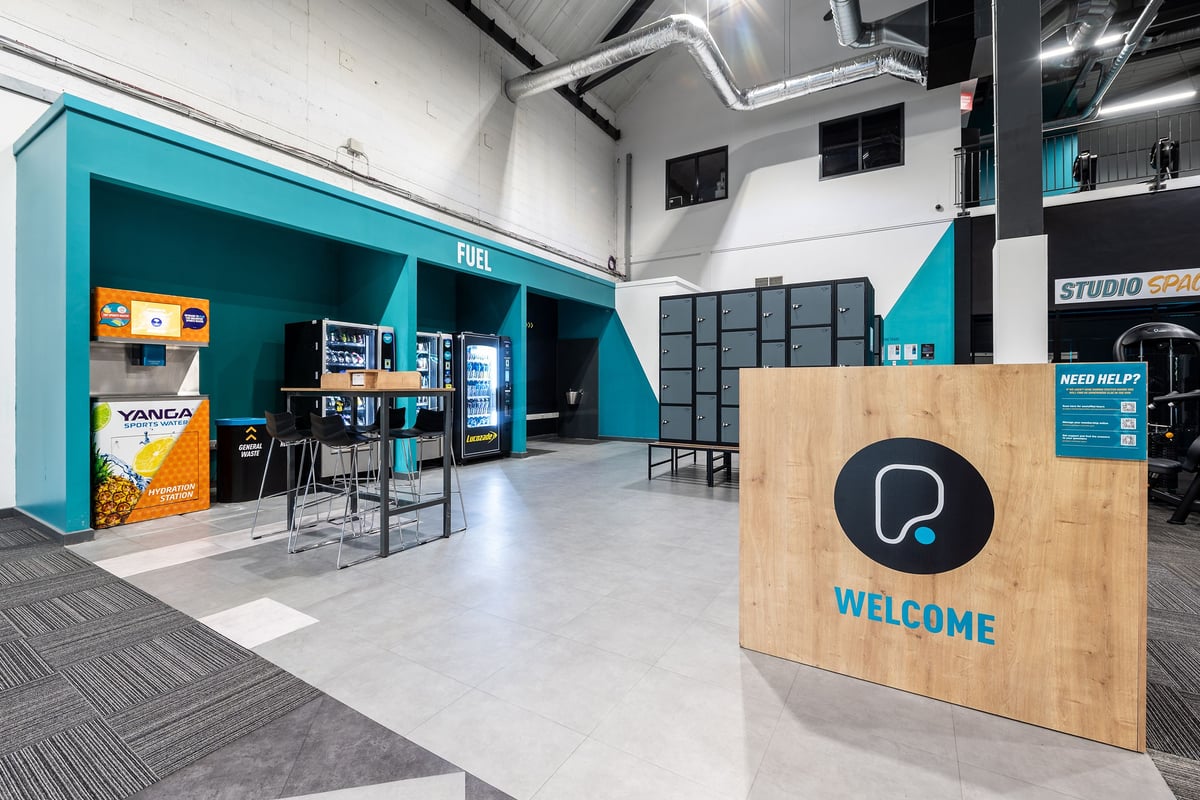 PureGym York: Gym reception area with vending machines, self-service kiosks, branded signage, and waiting area.