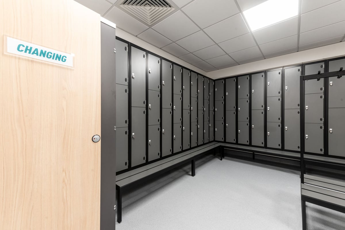 PureGym Bicester: Rows of lockers in a changing room with a sign indicating the area's purpose.