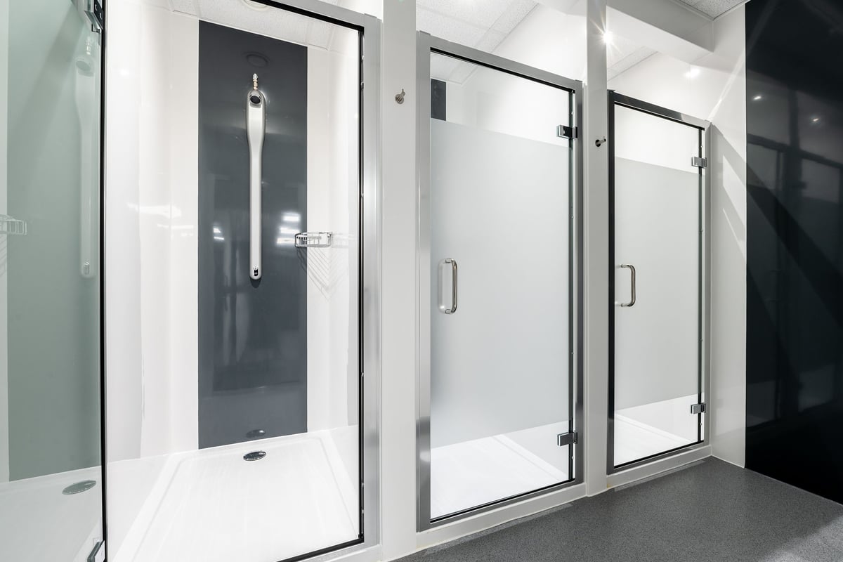 PureGym Birmingham Longbridge: Glass shower cubicles with sliding doors and grab rails.