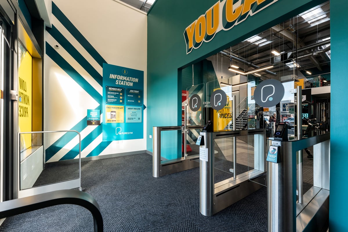 PureGym Consett: Information station, turnstiles, and a teal-coloured YouCycle logo interior setting.