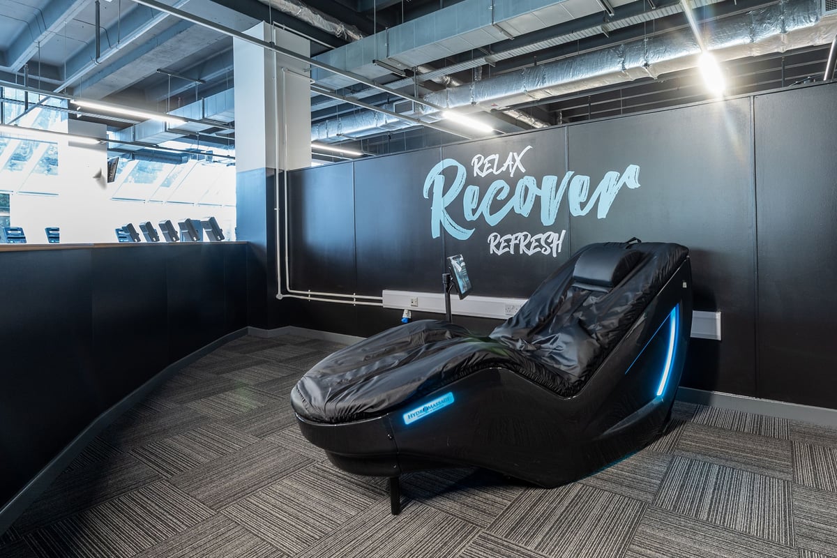PureGym Ipswich Buttermarket: Massage loungers with blue accent lighting in a recovery area.