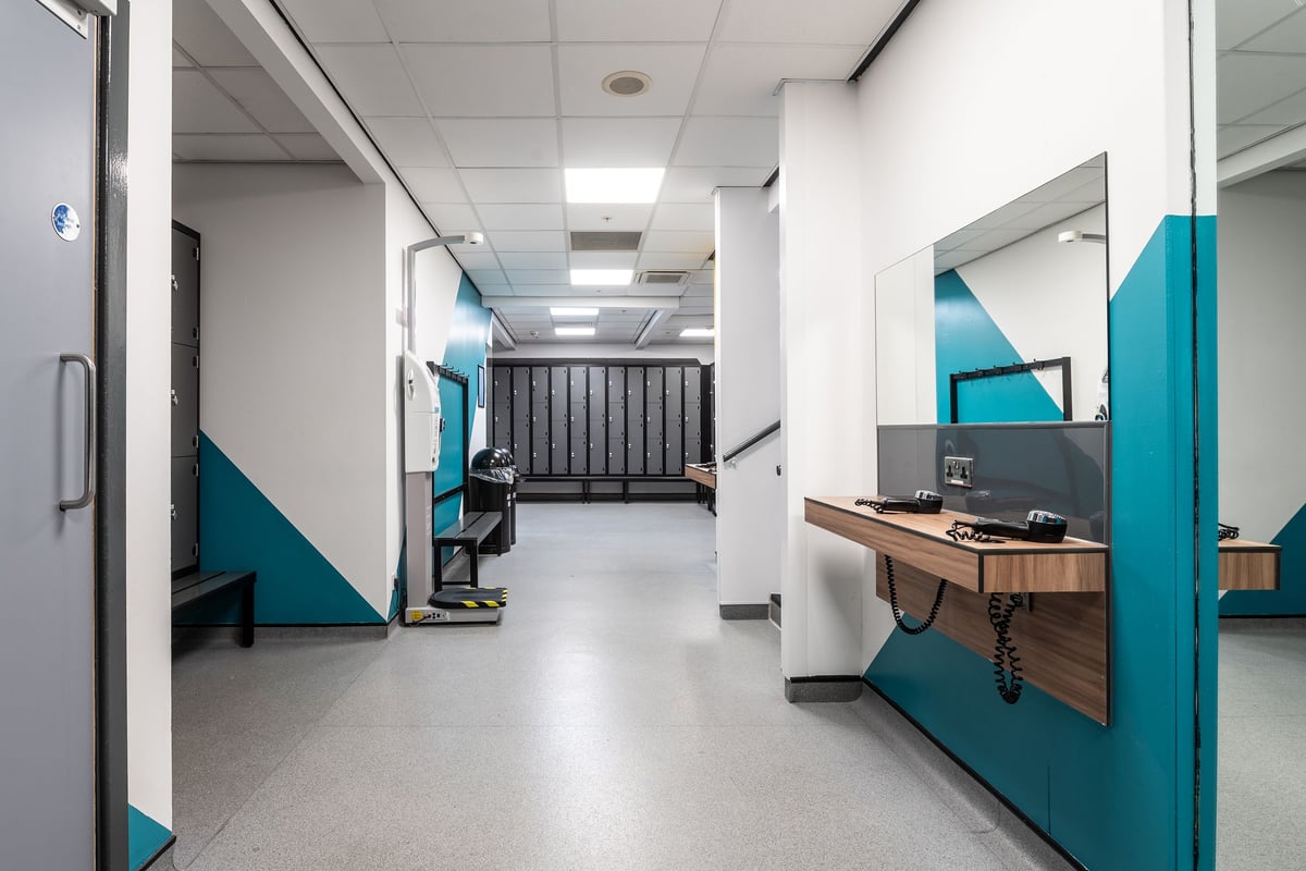 PureGym Manchester Spinningfields: Changing room with mirrors, hair dryers, lockers, and benches.