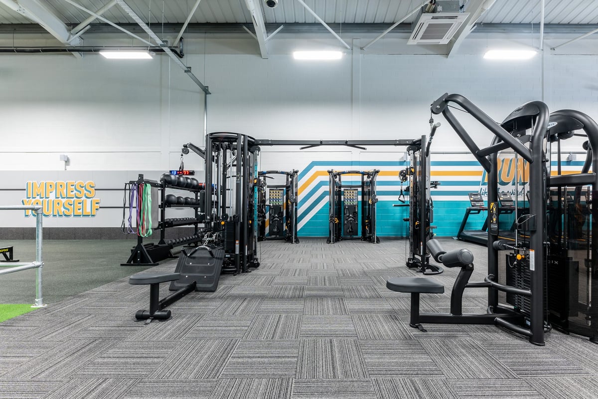PureGym Byfleet: Functional training area with cable machines, weight racks, benches, and rubberized flooring.