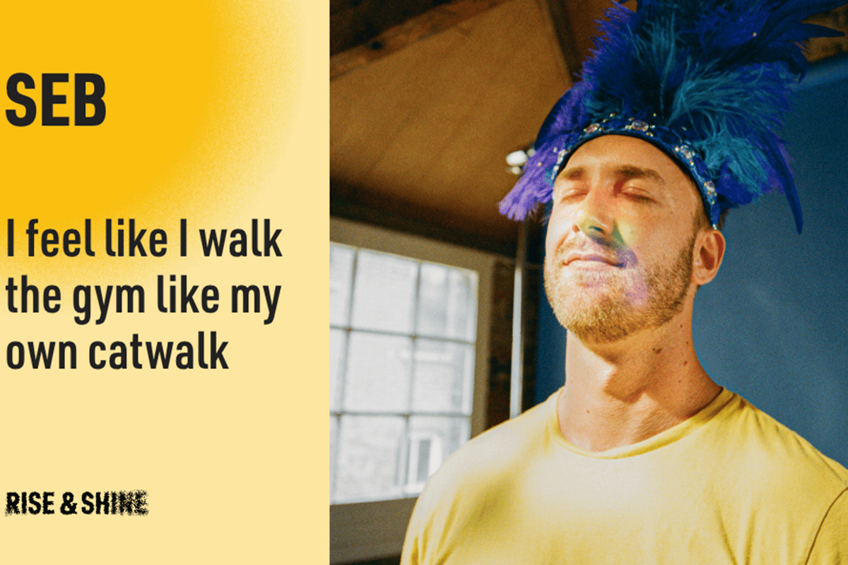 Man in yellow shirt with blue feathered headpiece and rainbow light on face