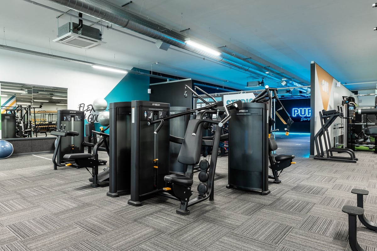 PureGym Witney: Free weight machines, cable stations, benches, and rubberized flooring in a modern gym setup.