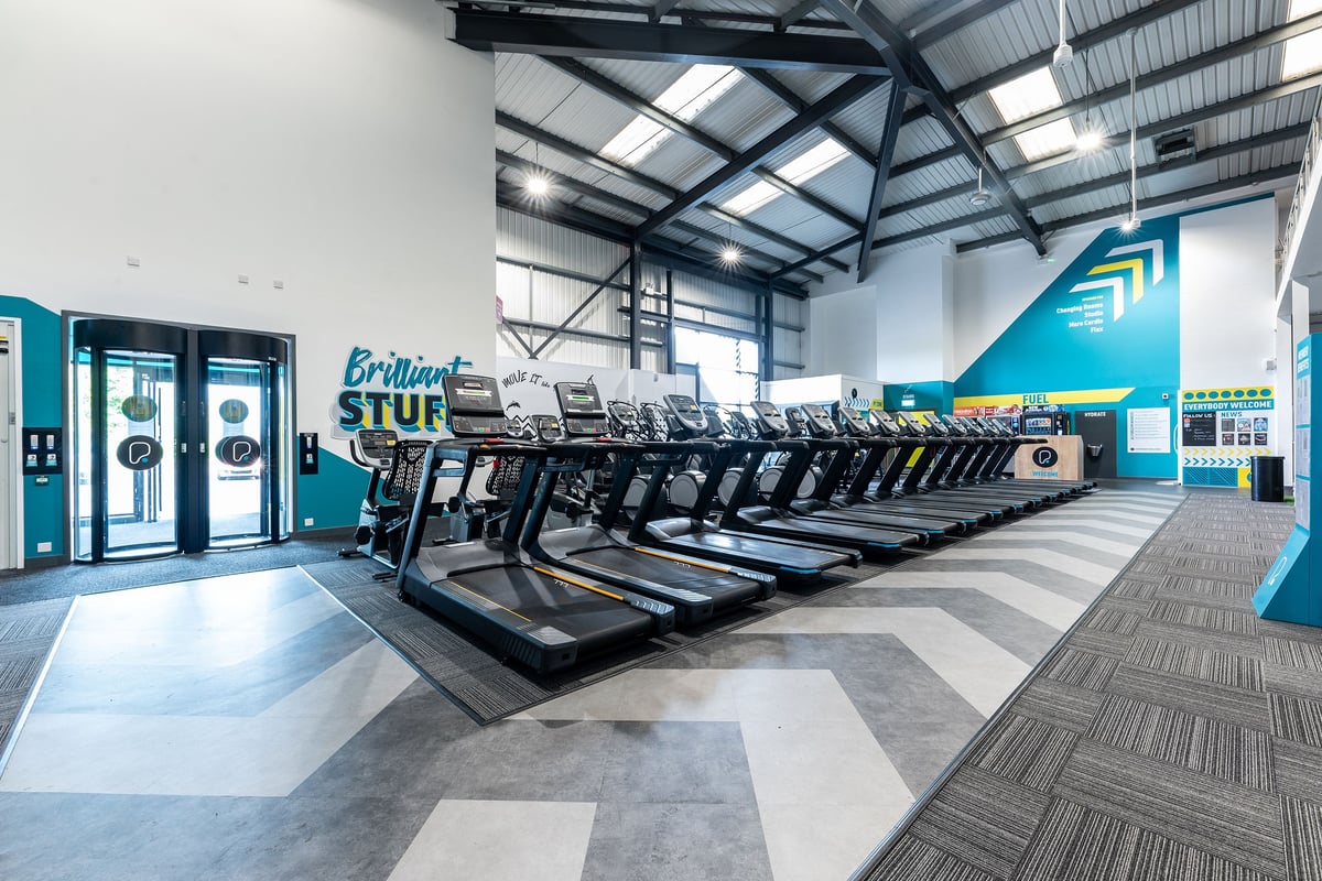 PureGym Leamington Spa: Rows of treadmills and Brilliant branded self-service kiosks in a bright gym facility.