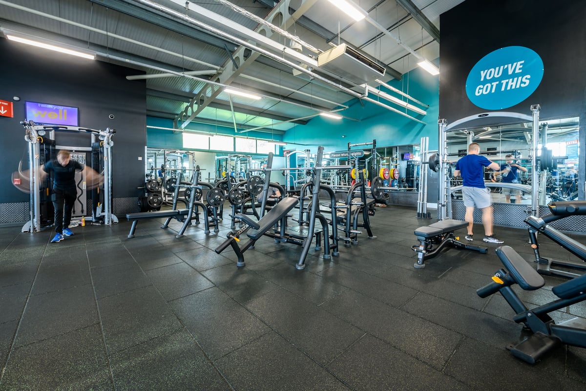 PureGym Manchester Moston: Weightlifting racks, benches, free weights, resistance machines in a brightly lit gym space.