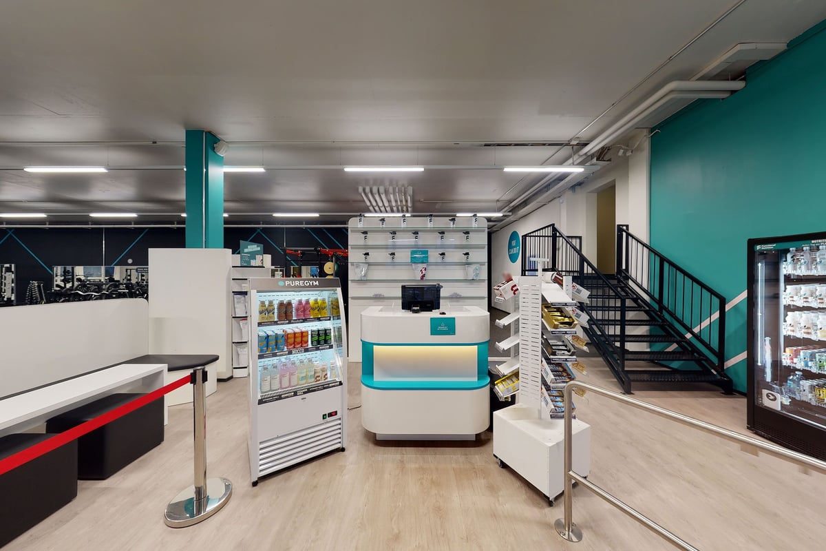PureGym Kriens: Gym entrance area with refreshment cooler and welcome podium.