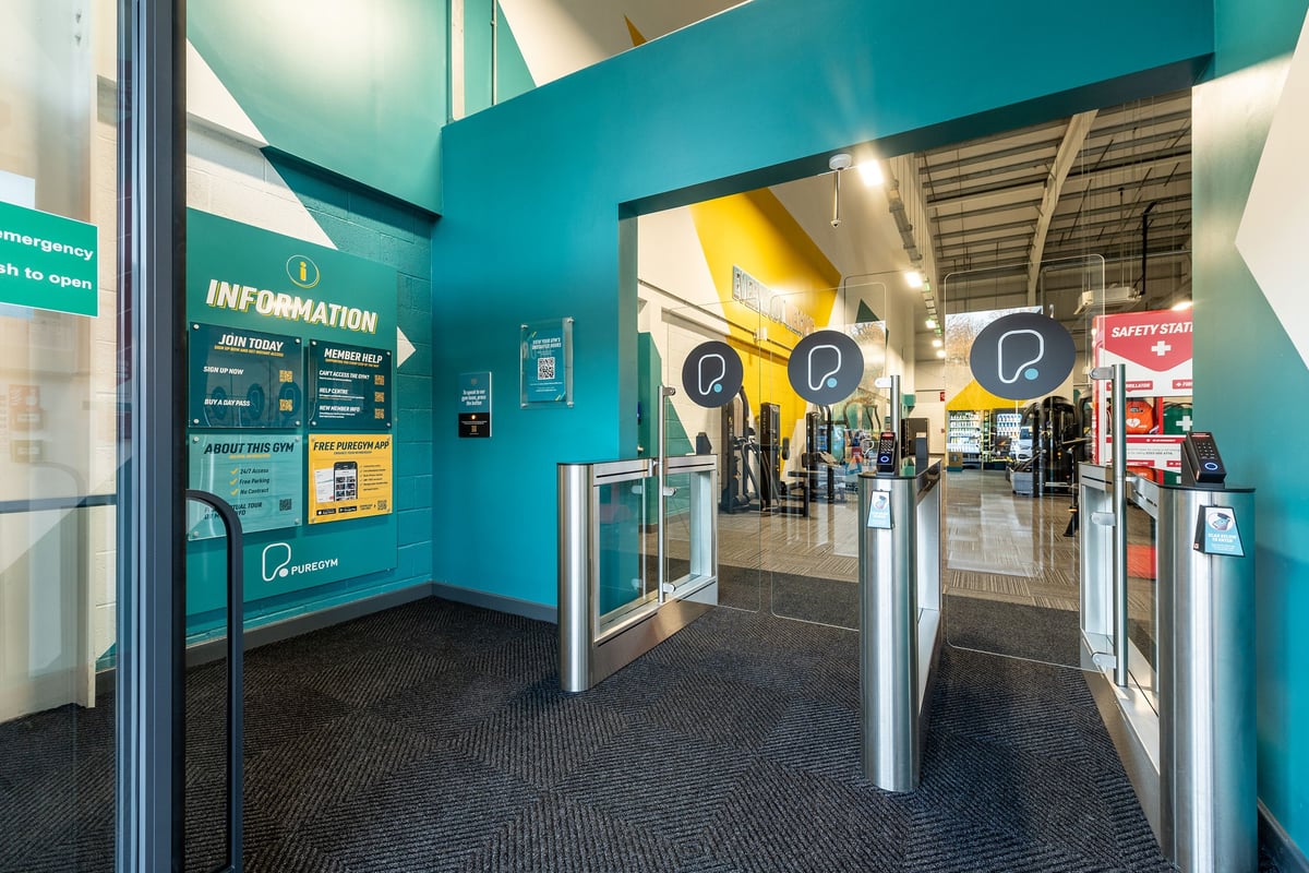 PureGym Alton: Entrance area with information signs, turnstiles, and queuing barriers.