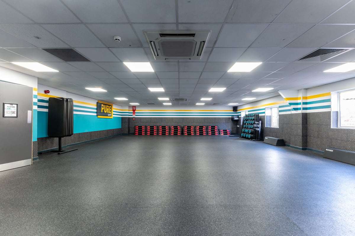 PureGym London Muswell Hill: Rows of red lockers, wall padding, rubberized flooring - an indoor gym changing area.